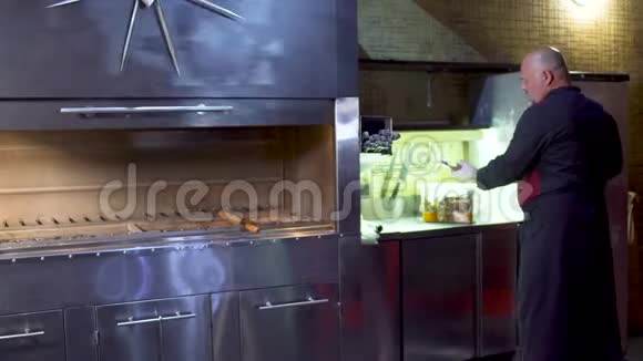 乌兹别克餐馆的厨师把生肉串在厨房的烤架上视频的预览图