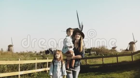 风车农场附近一个欧洲家庭的肖像戴帽子的漂亮女人和小男孩和女孩一起走4K视频的预览图