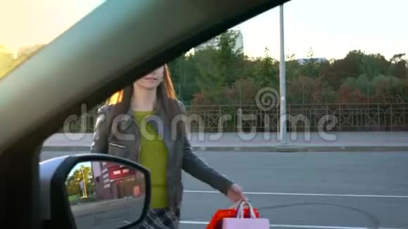 女人把购物袋放在汽车座椅上坐在其中打算开车离开视频的预览图