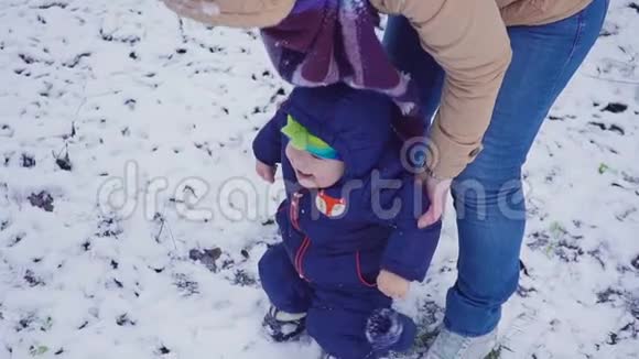 快乐的一岁男孩和他的母亲在冬天的森林里玩耍视频的预览图