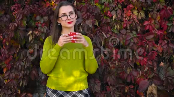 带眼镜的女人在温暖的秋日在户外喝茶或咖啡咖啡时间视频的预览图