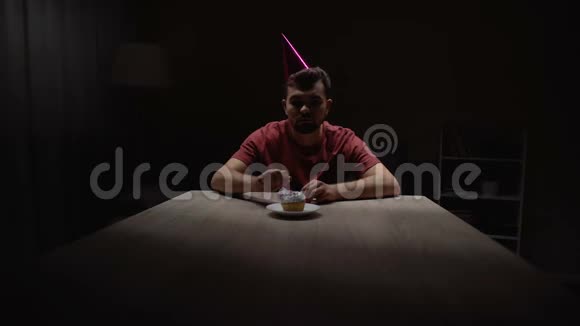 孤独的男人在生日蛋糕上点燃蜡烛独自坐在黑暗的房间里视频的预览图