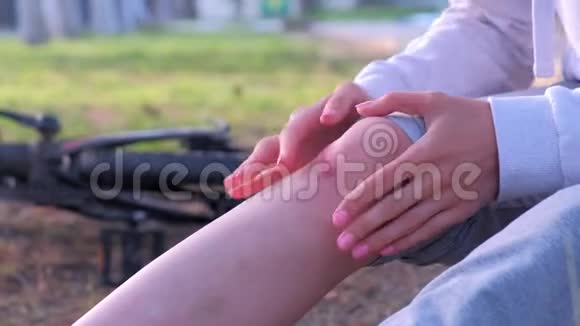 女人检查膝盖疼痛擦伤后从自行车上摔下来坐在地上视频的预览图