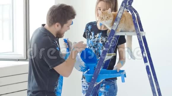 新房地产的概念一对年轻夫妇在他们的新房子里画猫并装修房间视频的预览图