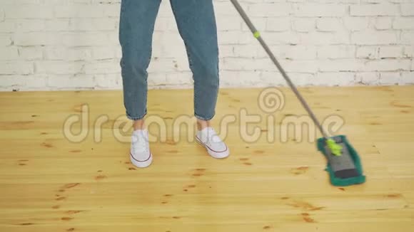 戴着防护手套的漂亮年轻女子在家里擦地板时用平的湿拖把的剪短图像视频的预览图