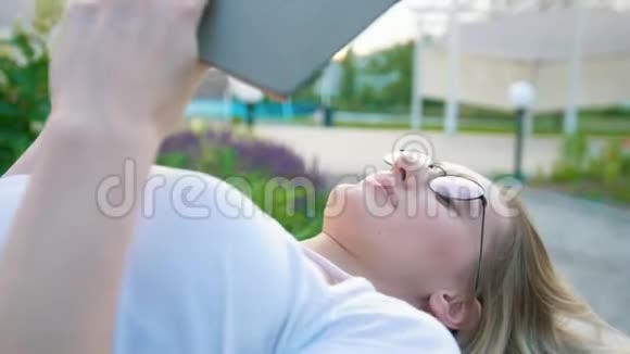 白人女孩躺在户外看书视频的预览图