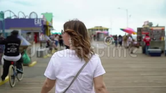 在圣莫尼卡码头散步的年轻女子视频的预览图