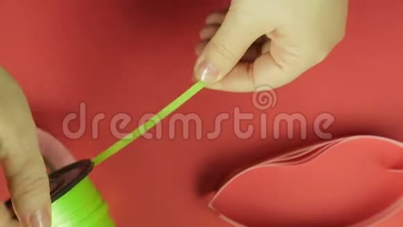 女性用剪刀从线圈中剪出绿色胶带红色背景视频的预览图