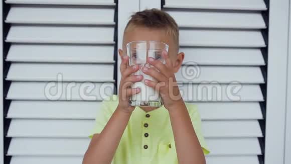 一个健康的男孩和一杯牛奶的肖像一个男孩正在白门附近喝牛奶健康的饮食这就是视频的预览图