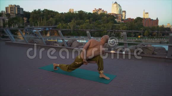 年轻的瑜伽士站在绿色的地毯上在早晨的城市景观背景下表演阿萨奴卷轴视频的预览图
