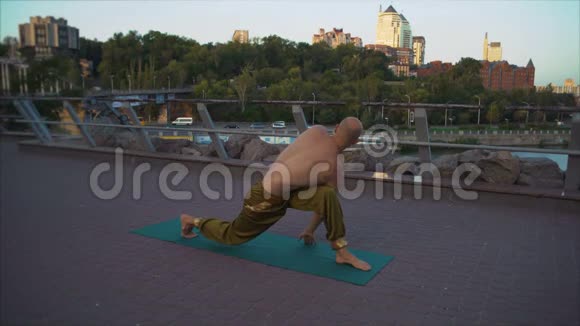 年轻的瑜伽士站在绿色的地毯上在早晨的城市景观背景下表演阿萨奴卷轴视频的预览图