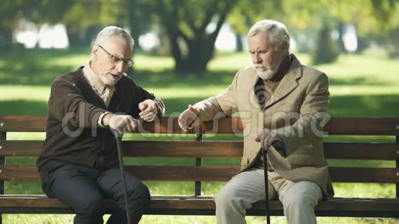 年长的朋友谈笑风生坐在公园的长凳上快乐的回忆视频的预览图