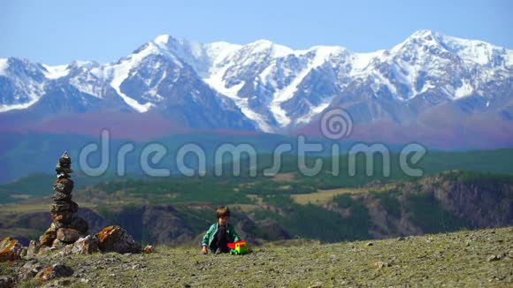 一个非常可爱的男孩在山上玩得很开心小帅哥在山顶上玩玩具车视频的预览图