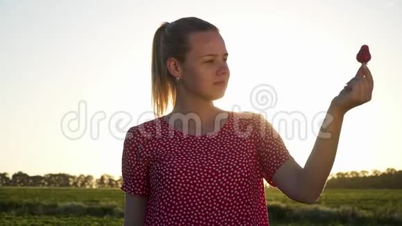 日落背景下带草莓的年轻女孩视频的预览图