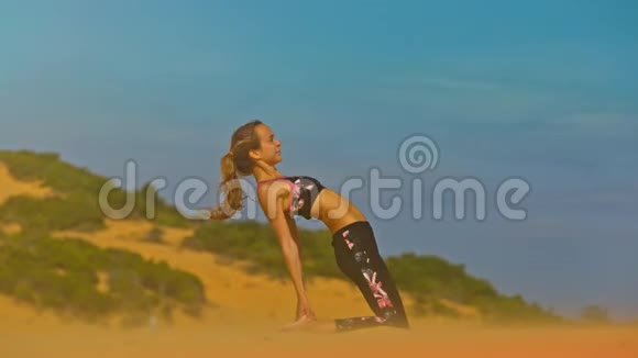无止境沙丘特写中微风中瑜伽姿势中的女孩视频的预览图
