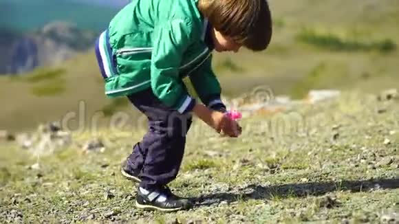 一个非常可爱的男孩在山上玩得很开心小帅哥在山顶上玩玩具马视频的预览图