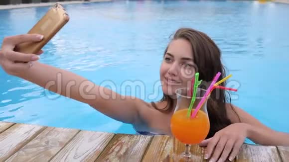 selfie度假时在昂贵的度假胜地游泳池里用手机拍下了微笑的女性照片视频的预览图