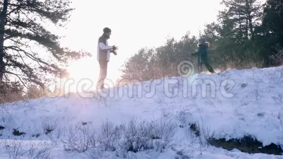 一家人在森林里玩得很开心小男孩碰到爸爸的手他们慢吞吞地落在雪地上视频的预览图