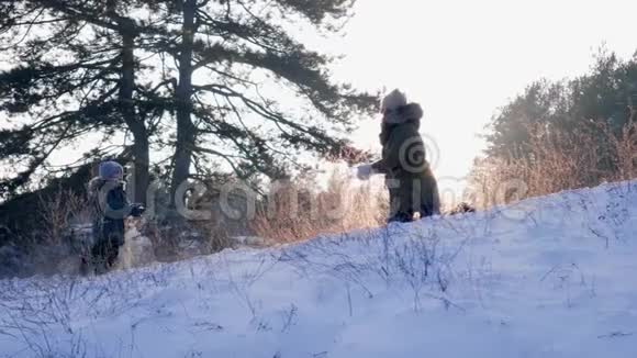 家庭户外男孩和妈妈一起玩背景美丽的冬季自然和日落视频的预览图