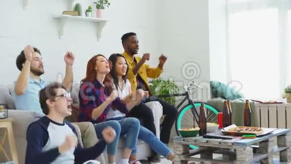 快乐的朋友体育迷在家里看体育比赛他们为最喜爱的球队加油鼓掌视频的预览图