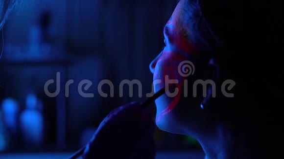 紫外线黑光在年轻女性脸上发光体加工冷蓝色的粉色染料视频的预览图