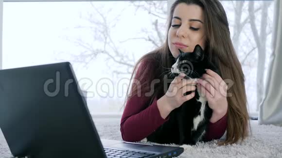 家庭舒适有猫的好女孩用笔记本电脑上网交流视频的预览图