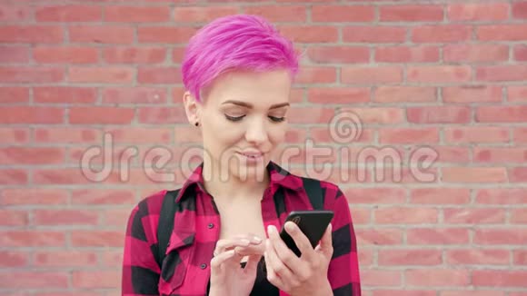 粉红头发的女人用电话对付砖墙视频的预览图