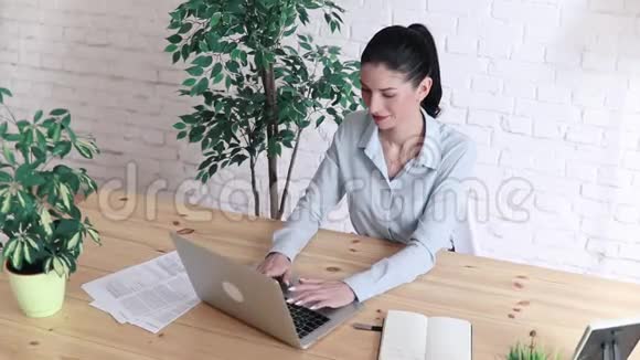 一个漂亮的商业女人在笔记本上做笔记的肖像拿着笔坐在工作场所视频的预览图