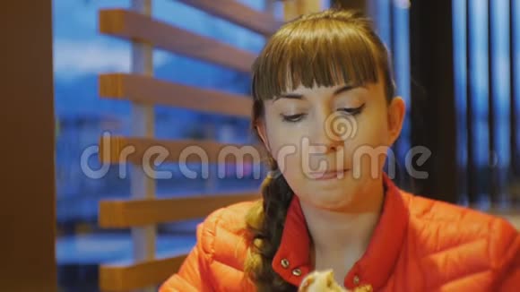 女人吃快餐在快餐店里一张迷人的女性咬人和咀嚼芝士汉堡的特写镜头视频的预览图