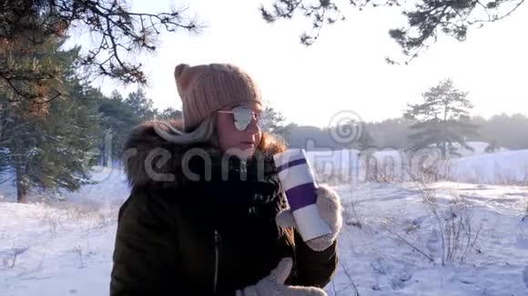 美丽的女孩正在森林里享受冬天在户外喝一杯热饮料视频的预览图