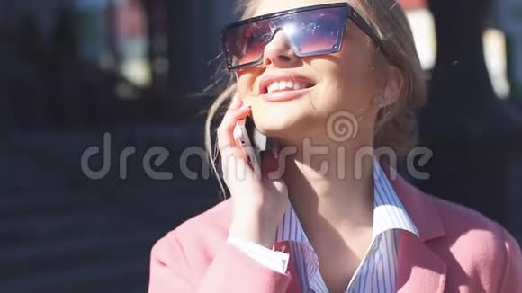 漂亮的女孩带着时尚的太阳镜看着户外视频的预览图