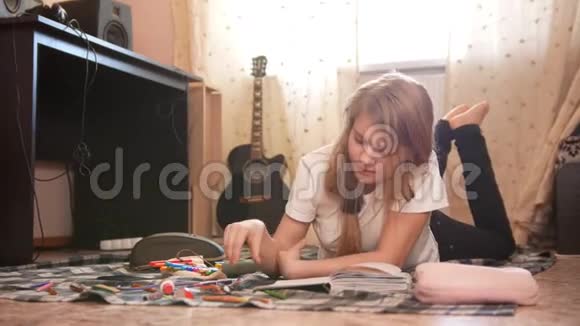十几岁的女孩躺在地上在家里画画视频的预览图
