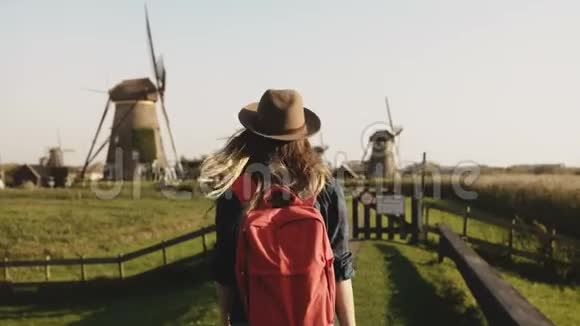 年轻的女商人在风车旁感到快乐成功的女企业家欣赏乡村磨坊农场的风景4K视频的预览图