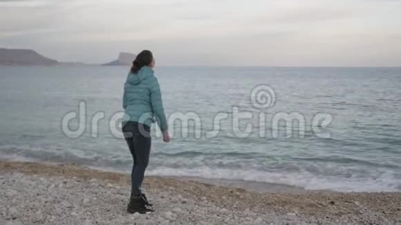 孤独寒冷海滩的女人高加索女人把石头扔进平静的大海视频的预览图