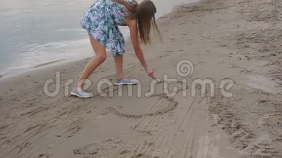 女孩在沙滩上的沙滩上画一颗心视频的预览图