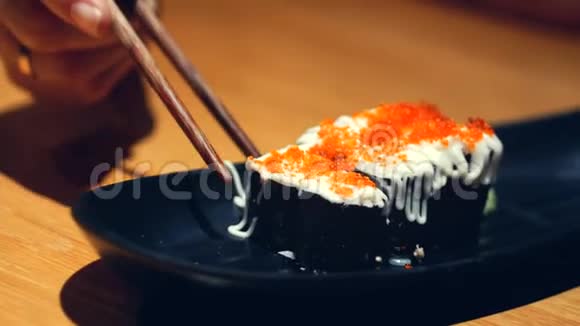 年轻的女人手拿棍子带走了寿司中国棍棒的概念寿司卷在黑暗的盘子上视频的预览图