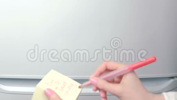 特写女人手贴黄色贴纸纸上面写着买牛奶面包鸡肉家庭笔记视频的预览图