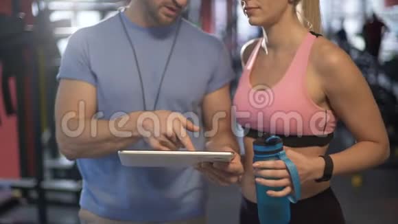 女人在和她的健身教练调情谈论健身房的健身时间表视频的预览图
