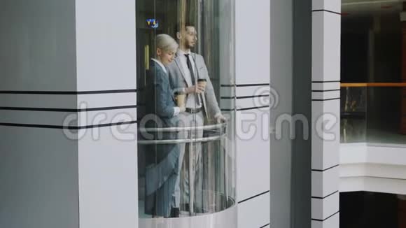 在现代商务中心商务女性和商务同事在移动电梯中交谈时倾斜下来视频的预览图