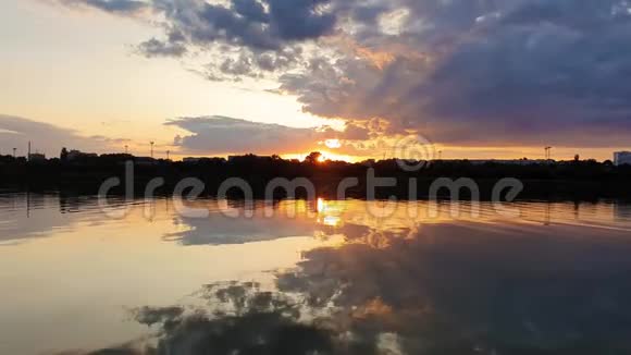 美丽的日落在城市的地平线上在一个寂静的夏天的傍晚倒影在平静的湖水上视频的预览图