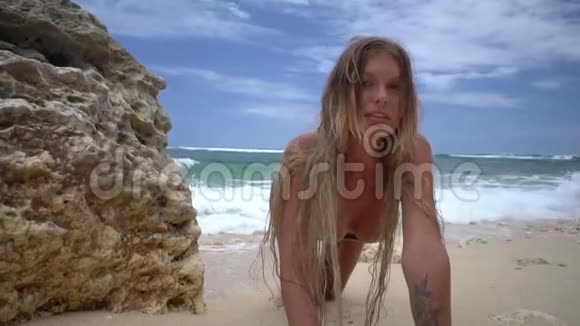 金发碧眼的女人站在四周摆姿势海浪拍打着她的后背沙滩上有沙滩蔚蓝视频的预览图