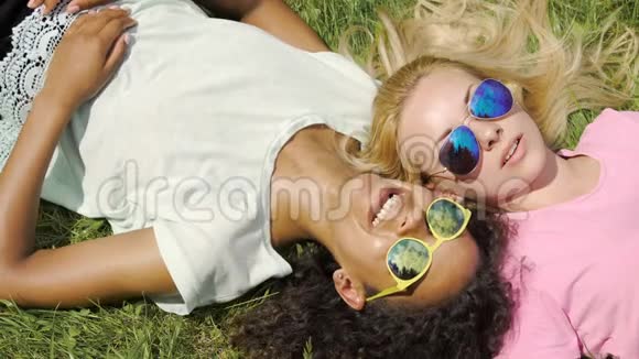 两个女朋友躺在草地上闲聊男人微笑友谊视频的预览图