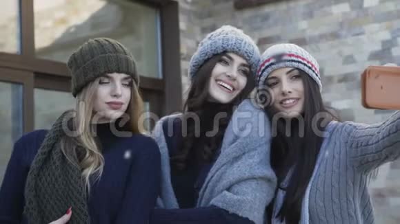 三个戴着帽子戴着围巾的漂亮女孩在院子里自拍视频的预览图