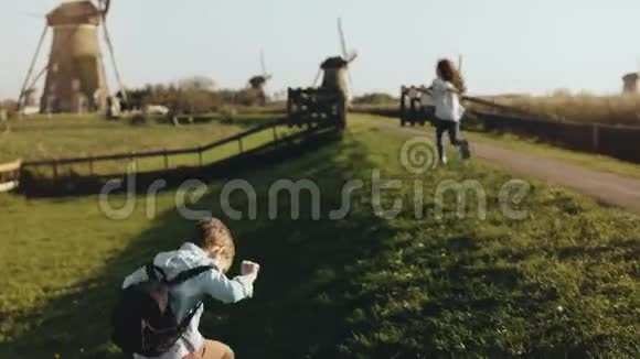 两个小孩在旧风车农场附近玩耍快乐的孩子们在乡村的风景中奔跑快乐和快乐4K视频的预览图