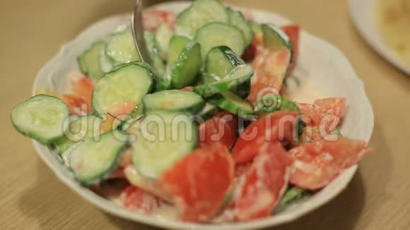 一个男人吃一份新鲜黄瓜和红西红柿的沙拉和白酱自制食物视频的预览图