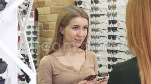 快乐的年轻美女在光学商店试戴太阳镜视频的预览图