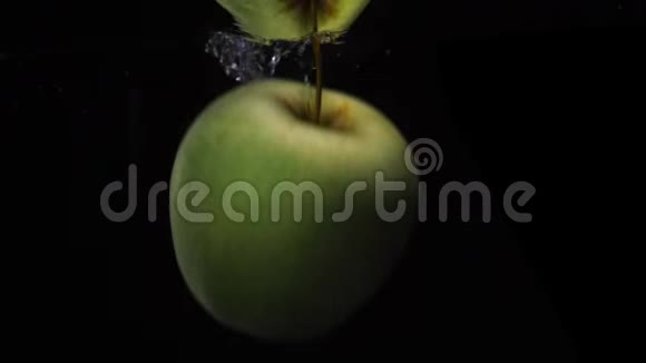 慢动作镜头绿苹果掉下来漂浮在水中黑色背景食物视频视频的预览图
