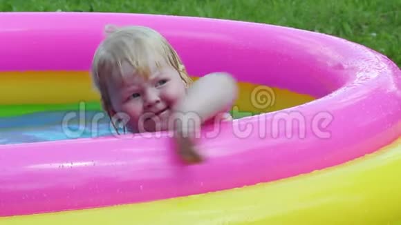 夏季娱乐活动女婴在院子里的充气游泳池里洗澡视频的预览图