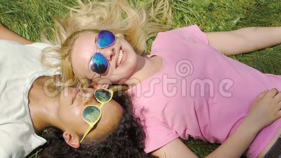 漂亮的多种族女孩在智能手机上自拍在公园的草坪上放松视频的预览图