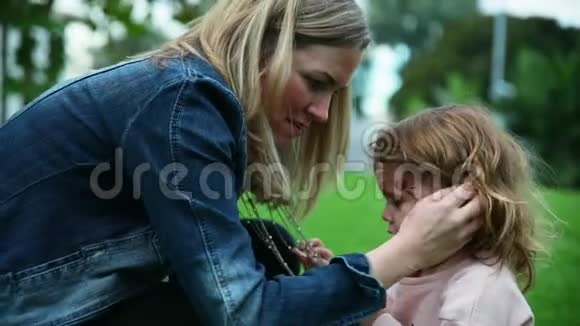 母女俩坐在一起女孩在玩妈妈的珠子妈妈拍拍女儿的头视频的预览图